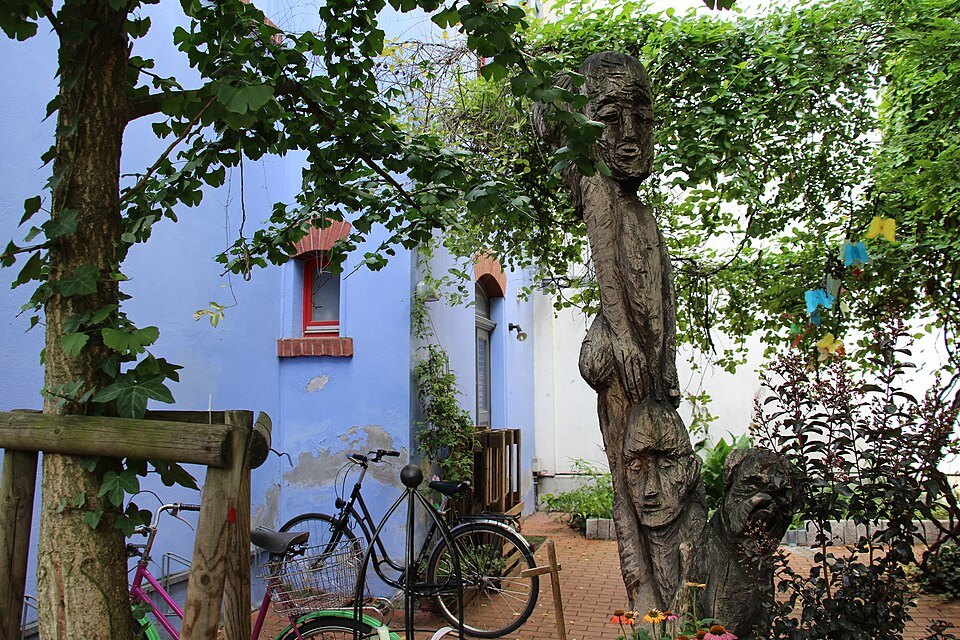 Carved wooden figures in a leafy courtyard